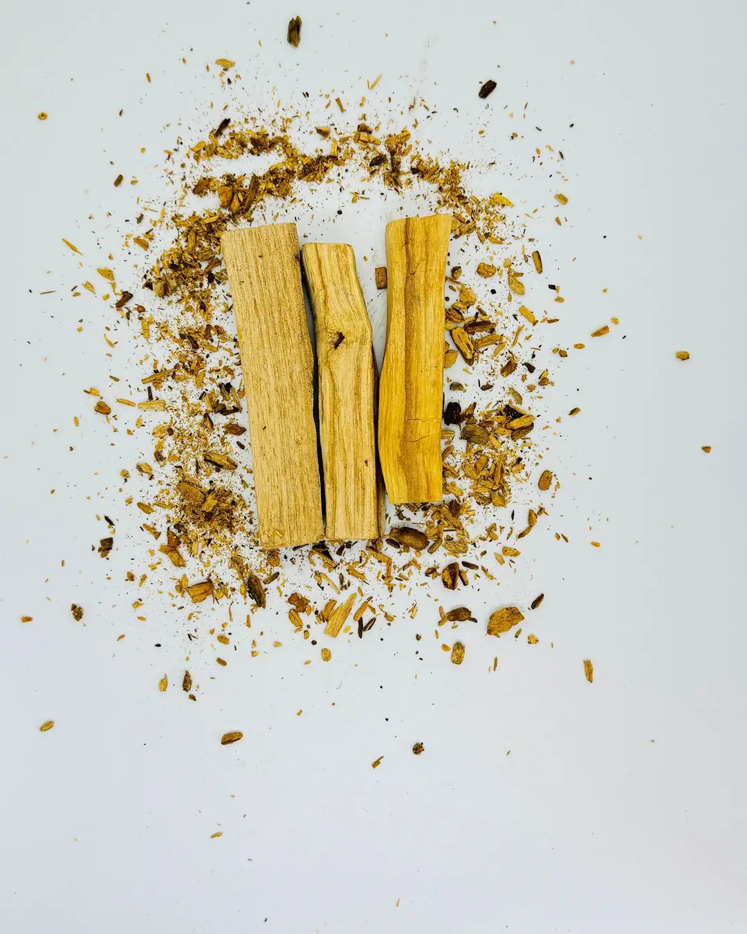Tres palitos de palo santo sobre un círculo de astillas y viruta.